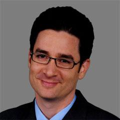 Yonatan Ben-Shalom is a man with short dark hair wearing glasses and a suit, smiling at the camera.